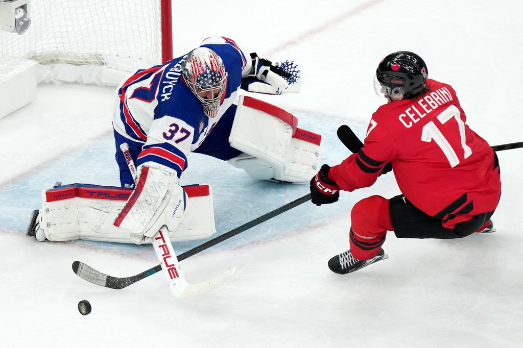 United States goalkeeper Connor Hellebuyck (37) blocks a shot by Canada's Macklin Celebrini (17) during the third period of the men's ice hockey gold medal game at the 2026 Winter Olympics in Milan, Italy, on Feb. 22, 2026. (AP Photo/Carolyn Kaster).